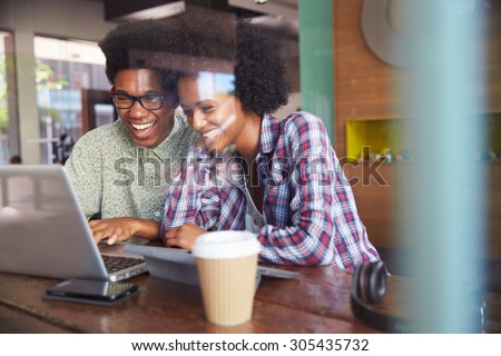 Two Young Businesspeople Working On Laptop In Coffee Shop