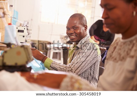 Smiling man sewing at a community workshop, South Africa