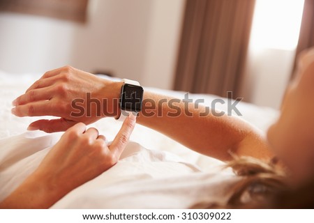 Woman Lying in Bed Whislt Checking The Time on Smart Watch