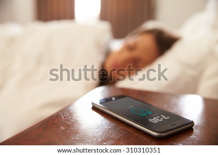 Woman Asleep In Bed Woken By Alarm On Mobile Phone