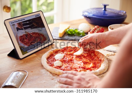 Person Following Pizza Recipe Using App On Digital Tablet