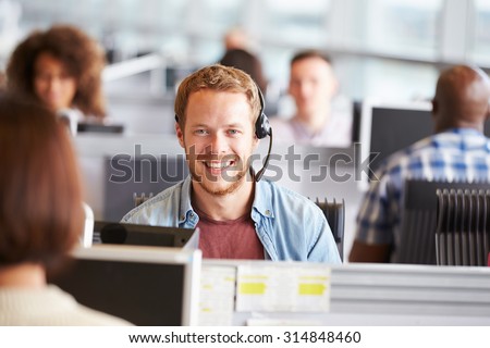 Young man working in a call centre, looking to camera