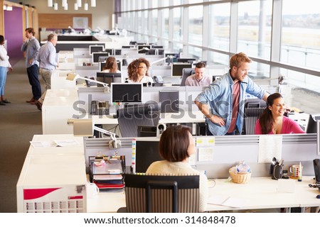 Casually dressed colleagues talking in an open plan office