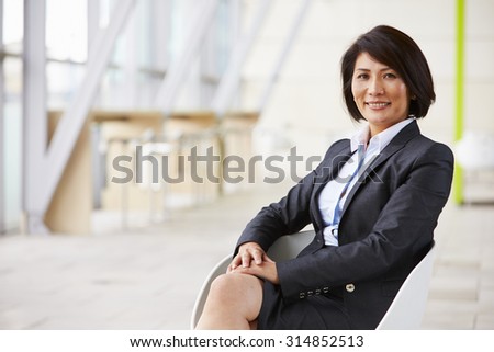 Portrait of smiling Asian businesswoman, sitting