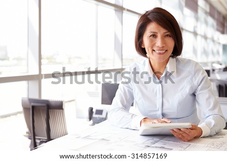Female architect using tablet computer, looking to camera
