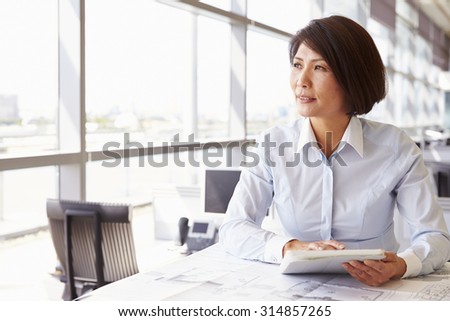 Female architect using tablet computer, looking away