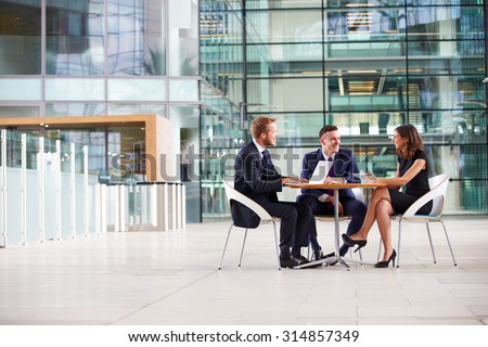 Three colleagues at a meeting in the foyer of a big business
