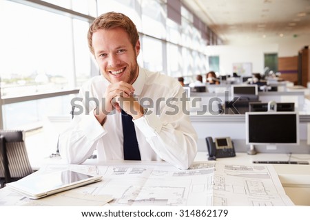 Young architect at work in an office, smiling to camera