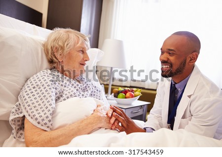Doctor Talking To Senior Female Patient In Hospital Bed