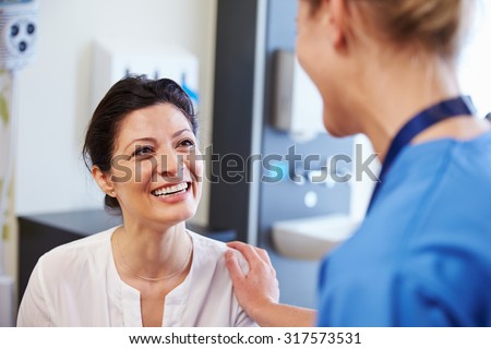 Female Patient Being Reassured By Doctor In Hospital Room
