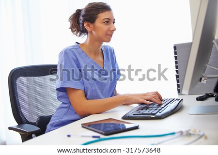 Female Doctor In Office Working At Computer