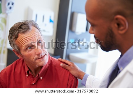 Male Patient Being Reassured By Doctor In Hospital Room