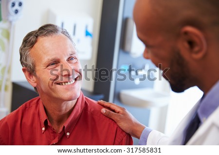 Male Patient Being Reassured By Doctor In Hospital Room