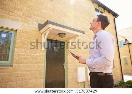 Male real estate agent looking up at a house exterior