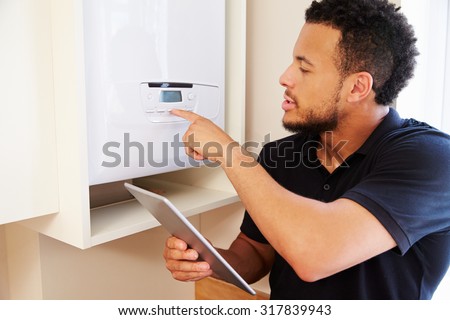 Technician servicing a boiler holding tablet computer