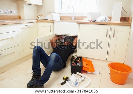 A plumber lying on his back to fix a kitchen sink