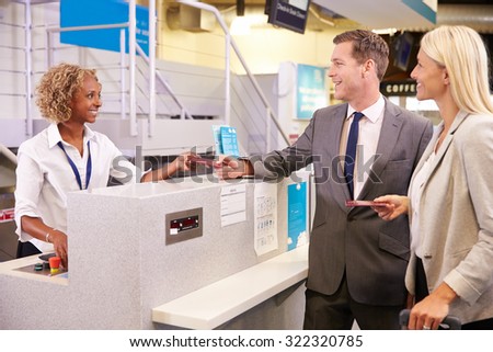 Couple At Airport Check In Desk Leaving On Business Trip