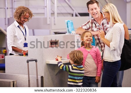 Family At Airport Check In Desk Leaving On Vacation