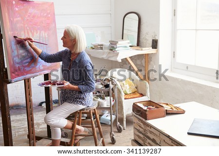 Female Artist Working On Painting In Studio