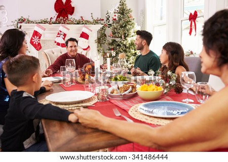 Family With Grandparents Saying Grace Before Christmas Meal