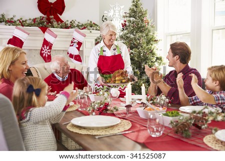 Grandmother Bringing Out Turkey At Family Christmas Meal