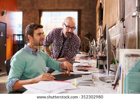 Designers Working Together At Desks In Modern Office
