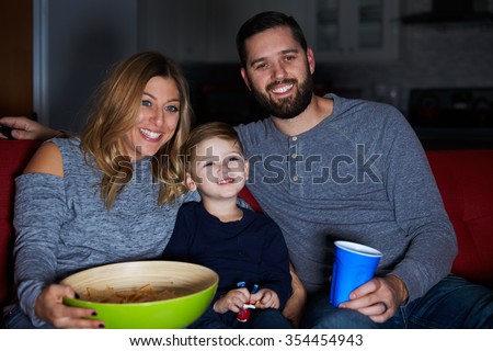 Family Sitting On Sofa Watching Television Together