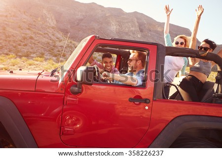 Friends On Road Trip Driving In Convertible Car