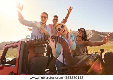 Friends On Road Trip Standing In Convertible Car