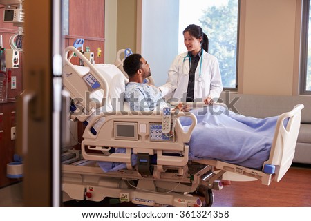Female Doctor Talking To Male Patient In Hospital Bed