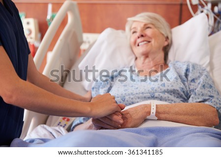 Close Up Of Hospital Nurse Holding Senior Patient's Hand