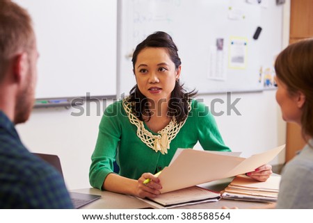 Teacher at desk talking to adult education students