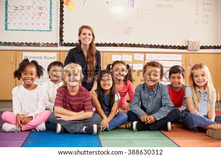 Teacher and elementary school kids sitting on classroom floor