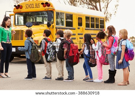 Teacher and a group of elementary school kids at a bus stop
