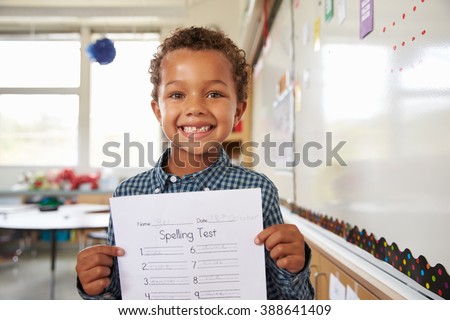 Portrait of elementary school boy holding up his test paper