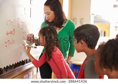 Pupil writing on the board at elementary school maths class