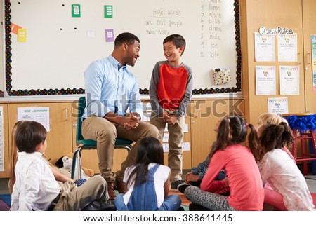 Schoolboy at front of elementary class talking with teacher