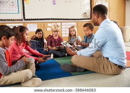 Elementary school class sitting cross legged using tablets