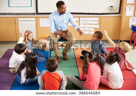 Elementary school kids sitting around teacher in a lesson