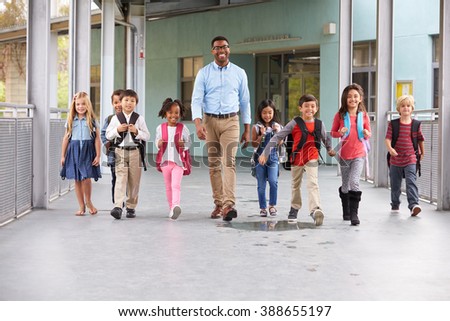 Male teacher walking in corridor with elementary school kids