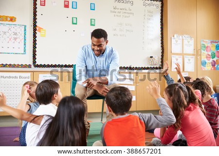 Elementary school kids sitting around teacher in a classroom