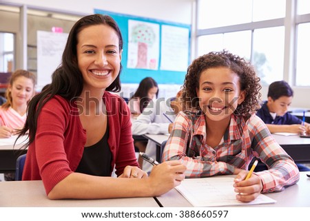 Portrait of teacher with elementary school girl at her desk