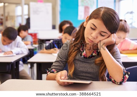 Bored girl reading tablet in elementary school class