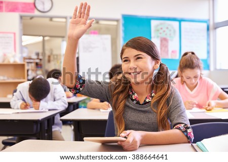 Girl with tablet raising hand in elementary school class