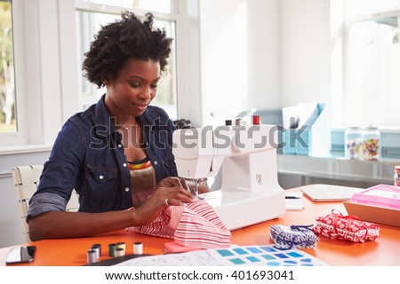 Young black woman stitching fabric using a sewing machine