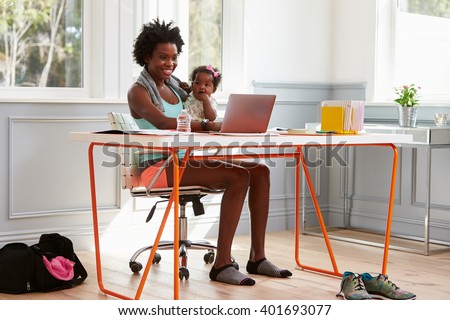 Woman holding child using computer at home after exercising