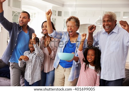 Multi generation black family watching sport on TV celebrate