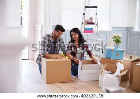 Hispanic Couple Moving Into New Home And Unpacking Boxes