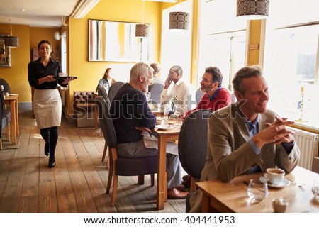 Customers at tables and waitress in busy restaurant interior
