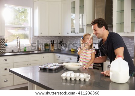 Girl putting cake mix on dadÃ¢??s nose while they bake together